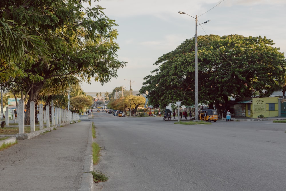 a street lined with trees and people standing on the side of the road