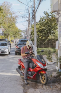 a man sitting on a red motorcycle on a city street