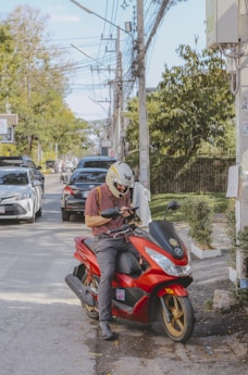 a man sitting on a red motorcycle on a city street