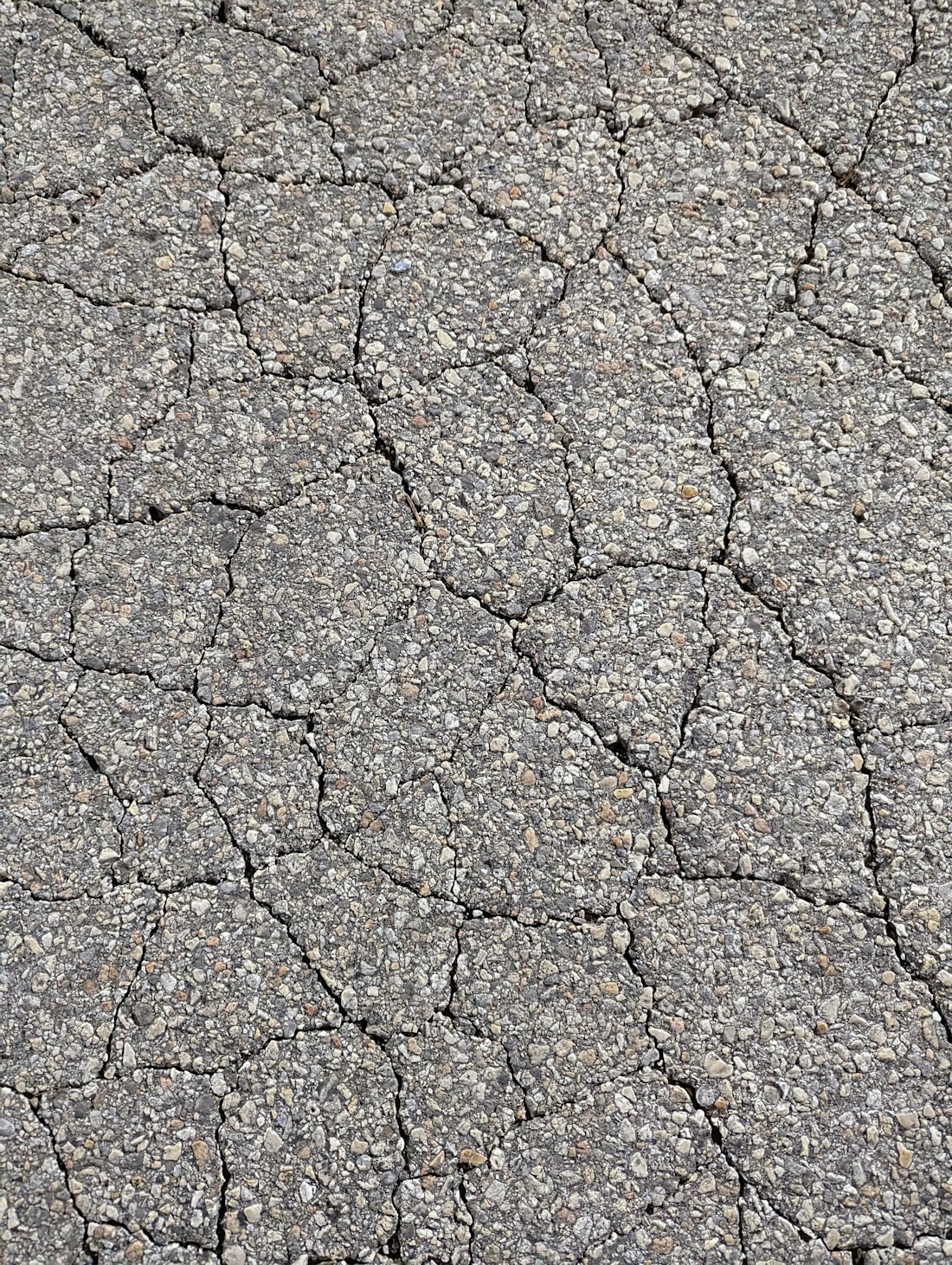 Old tarmac surface crazed with cracks