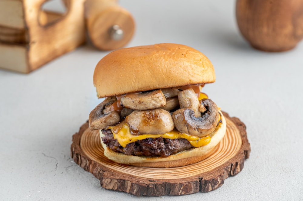 a cheeseburger with mushrooms on a wooden plate