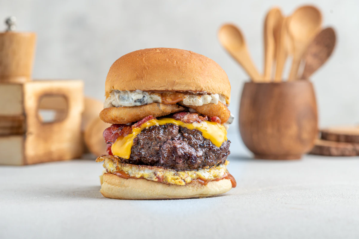 Gourmet cheeseburger on a soft brioche-style bun with melted cheddar, crispy bacon and creamy sauce