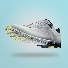 A single sports shoe is prominently displayed against a seamless, light turquoise background. The shoe features a sleek design with a gradient of light gray to dark gray tones, and is equipped with a distinctive CloudTec sole for cushioning. The branding logo is subtly visible on the side.