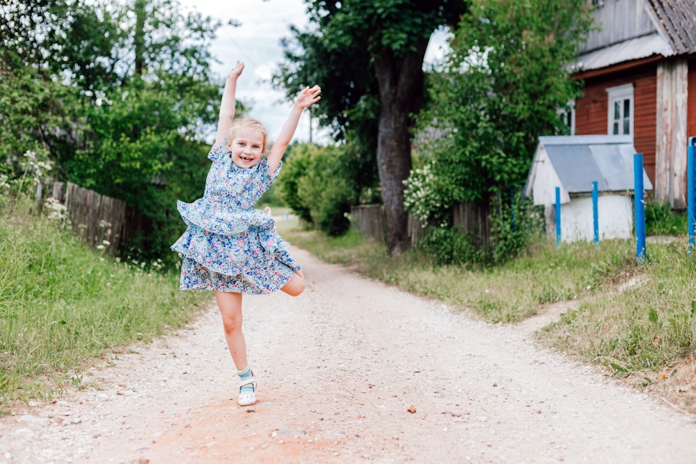 a little girl running down a dirt road