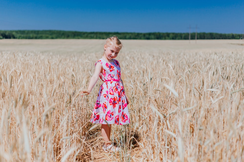 a little girl standing in a field of wheat