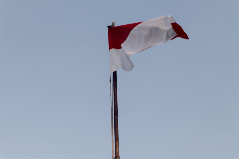 a red and white flag flying in the sky