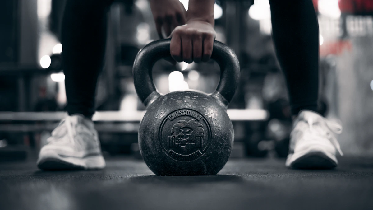 Osoba trzymająca odważnik kettlebell w ciemnej siłowni