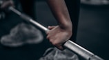 Close-up of a coach’s hands adjusting an athlete’s grip on the barbell during a clean and jerk session.
