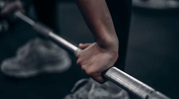 Close-up of hands gripping a barbell with golden particles softly glowing in the background.
