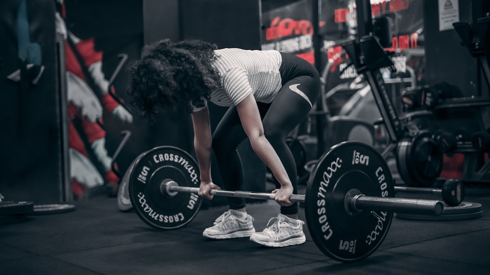 a woman lifting a barbell in a gym