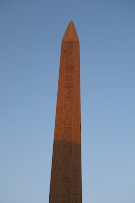 Intricate carvings on an ancient Egyptian obelisk standing tall amidst desert sands.