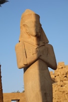 A mysterious stone statue standing guard in an overgrown archaeological site.