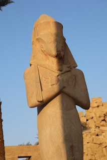 A mysterious stone statue standing guard in an overgrown archaeological site.
