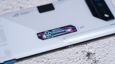 A sleek, modern smartphone with futuristic design elements and a digital display panel showing graphics and numbers, placed on a textured surface.