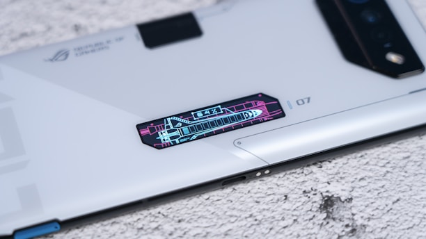 A sleek, modern smartphone with futuristic design elements and a digital display panel showing graphics and numbers, placed on a textured surface.