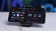 A smartphone mounted on a stand displays a screen showing performance metrics including CPU temperature, GPU temperature, memory usage, and cooler information. The interface design uses a futuristic style with red and blue accents.
