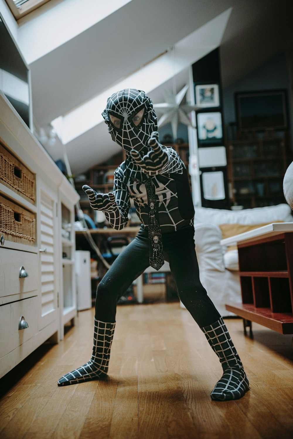 a person in a spider suit standing on a hard wood floor
