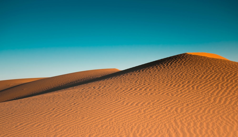 a sand dune with a blue sky in the background