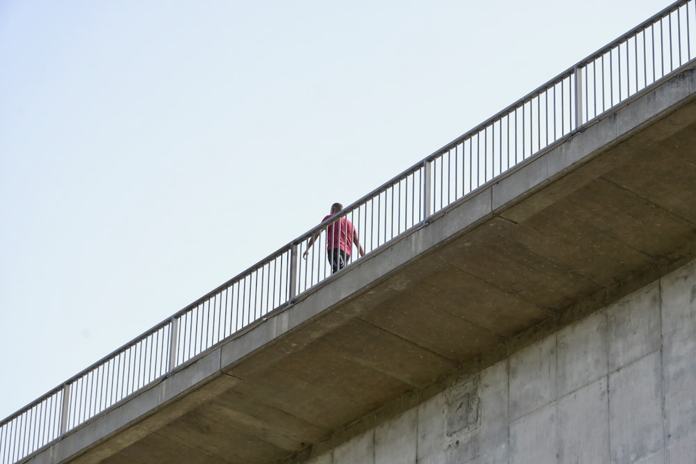 a man walking across a bridge with a skateboard