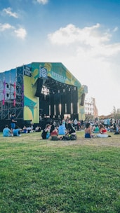 A vibrant outdoor stage set up in a lush green area with people enjoying live music.