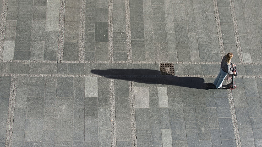 a woman walking down a sidewalk with a suitcase