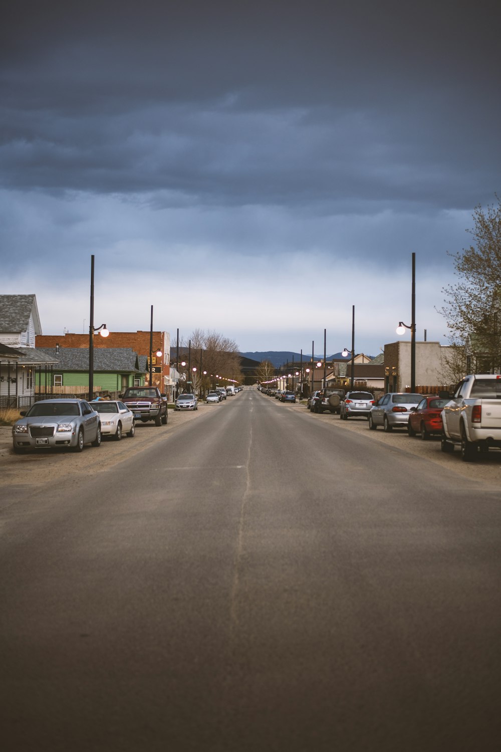 a street lined with parked cars under a cloudy sky