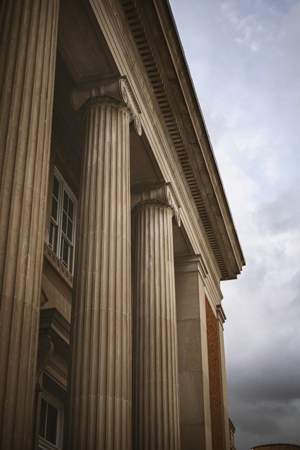 a tall building with columns and a clock on the side of it