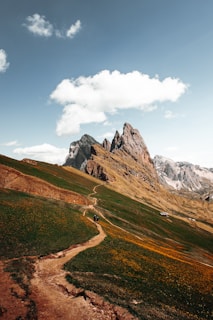 Visitors exploring a site visit, walking along a dirt path with mountains in the background.