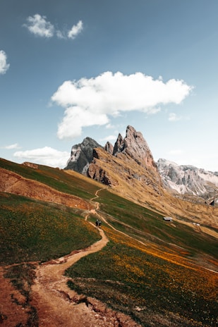 Visitors exploring a site visit, walking along a dirt path with mountains in the background.