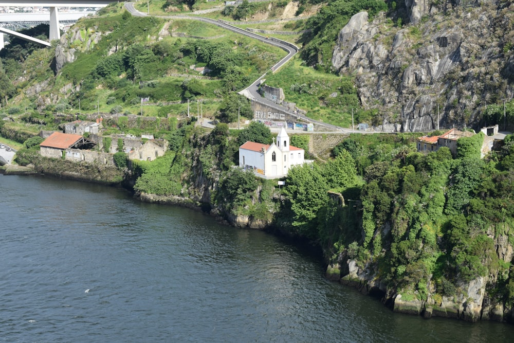 a river with a bridge over it next to a lush green hillside