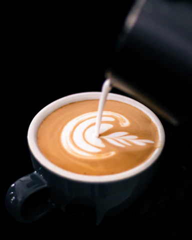 Close-up of a barista crafting a latte with intricate foam art.