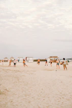 Players chatting and organizing their team on a mobile app during a break on an outdoor beach soccer field.