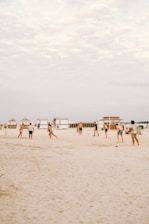 A group of athletes practicing futevôlei on a sunny beach.
