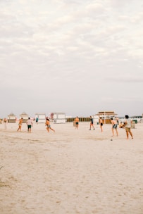 A group of athletes practicing futevôlei on a sunny beach.