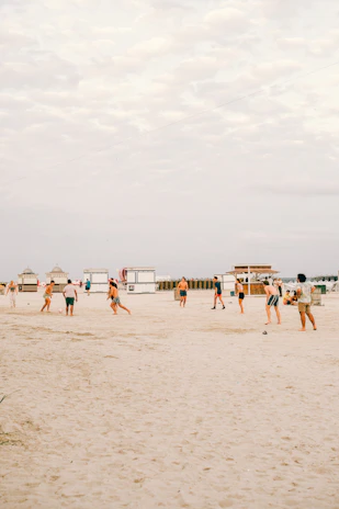 A close-up of a beach soccer match with players diving for the ball on golden sand.