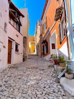 A narrow cobblestone street lined with whitewashed houses and colorful flowers in Vieste