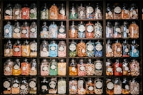 Close-up of colorful candy jars lined up on wooden shelves in a cozy shop.