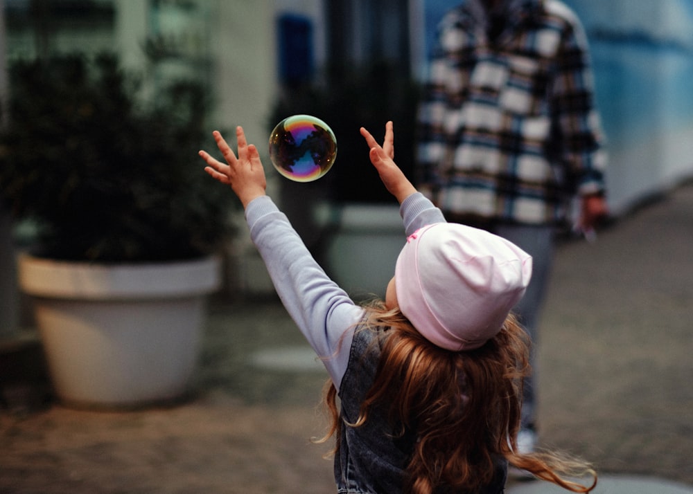 a little girl is playing with a bubble