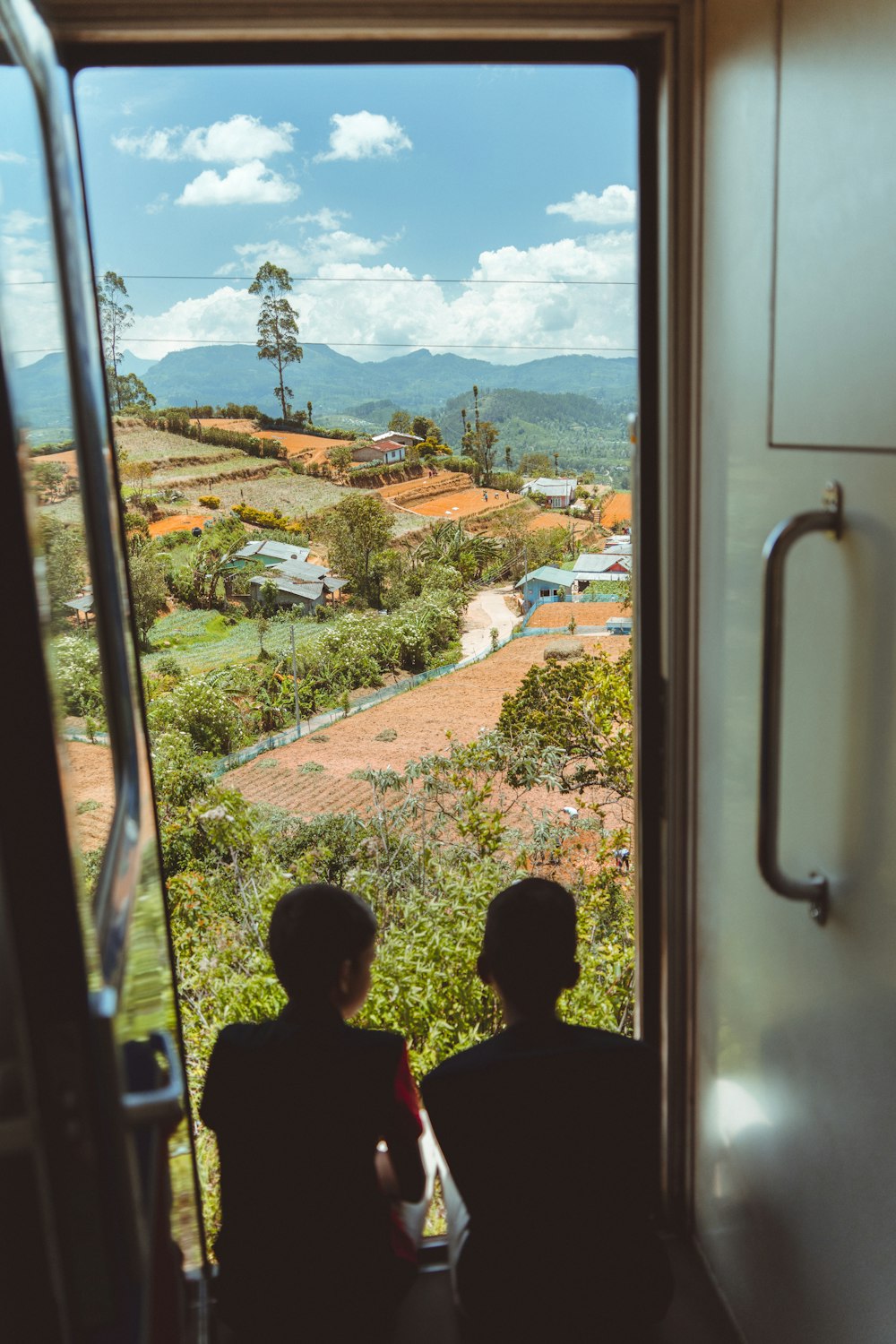 two people sitting on a train looking out a window