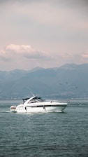 A sleek motorboat cruising on a calm lake under clear skies.
