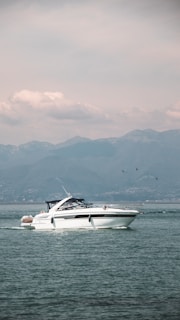 A sleek boat cutting through sparkling water on a sunny day, with mountains in the background.