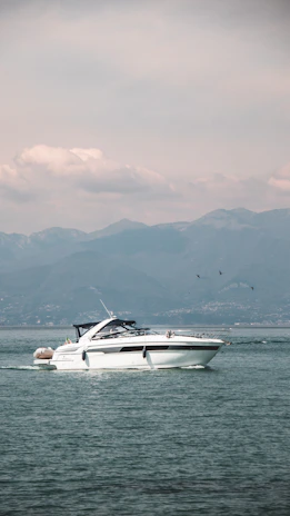 Overhead shot of sleek electric boats gliding silently in formation near a sunlit Mediterranean coastline.