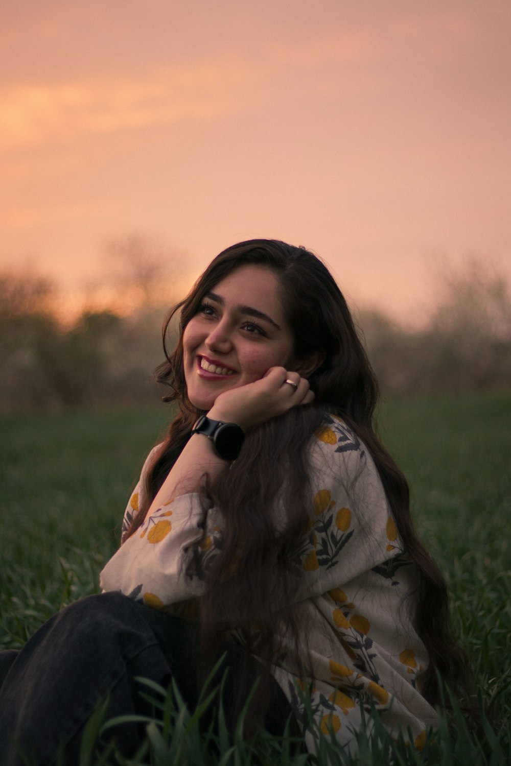 a woman sitting in the grass smiling at the camera