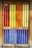 A set of wooden doors featuring vertical slats of colorful stained glass panels. The glass sections include rich hues of red, yellow, orange, and blue, creating a vibrant and eye-catching effect. The wooden frame has a natural finish, complementing the bright colors and adding warmth to the visual composition.