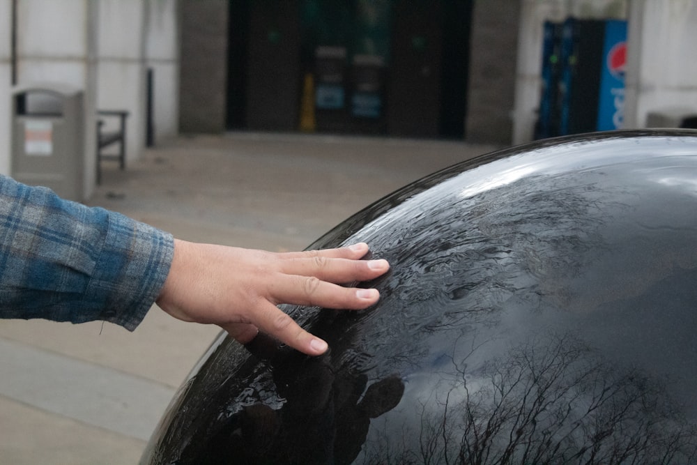 a person's hand on the top of a black object