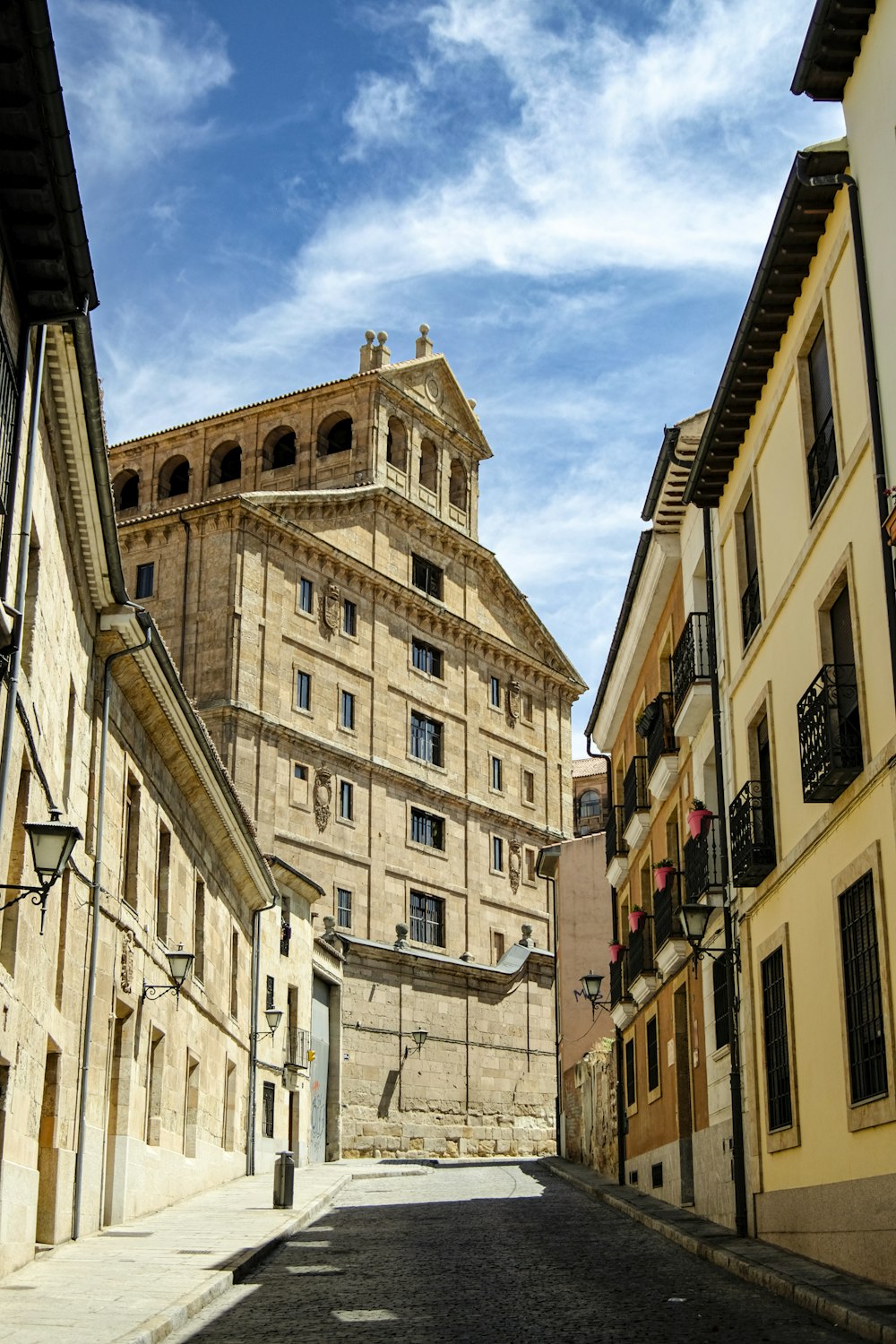 a narrow street with buildings and a clock tower in the background