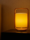 Close-up of a minimalist wooden ambient lamp casting warm light on a textured surface.