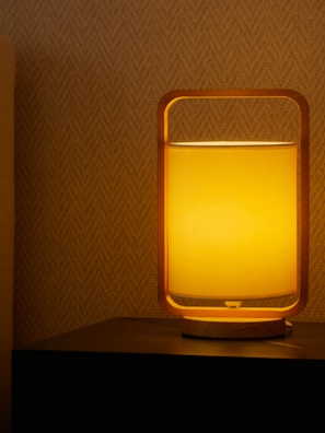 Close-up of a minimalist wooden ambient lamp casting warm light on a textured surface.