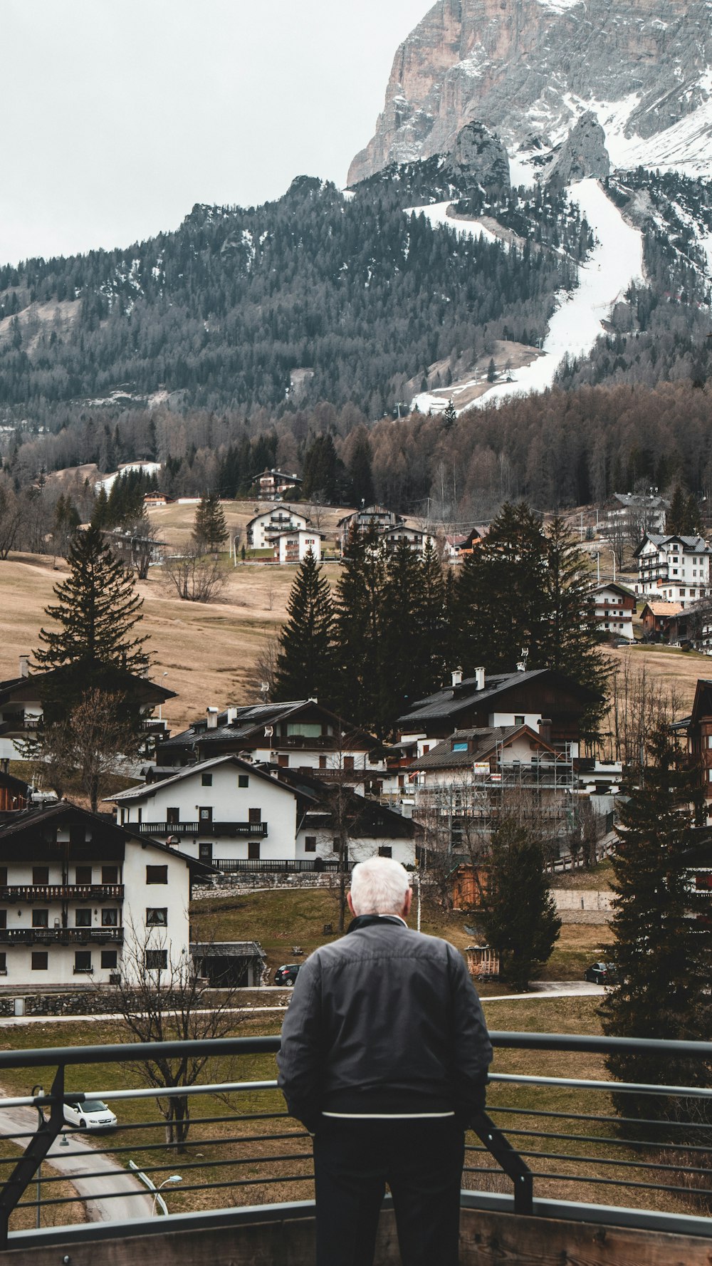 a man standing on top of a balcony next to a mountain