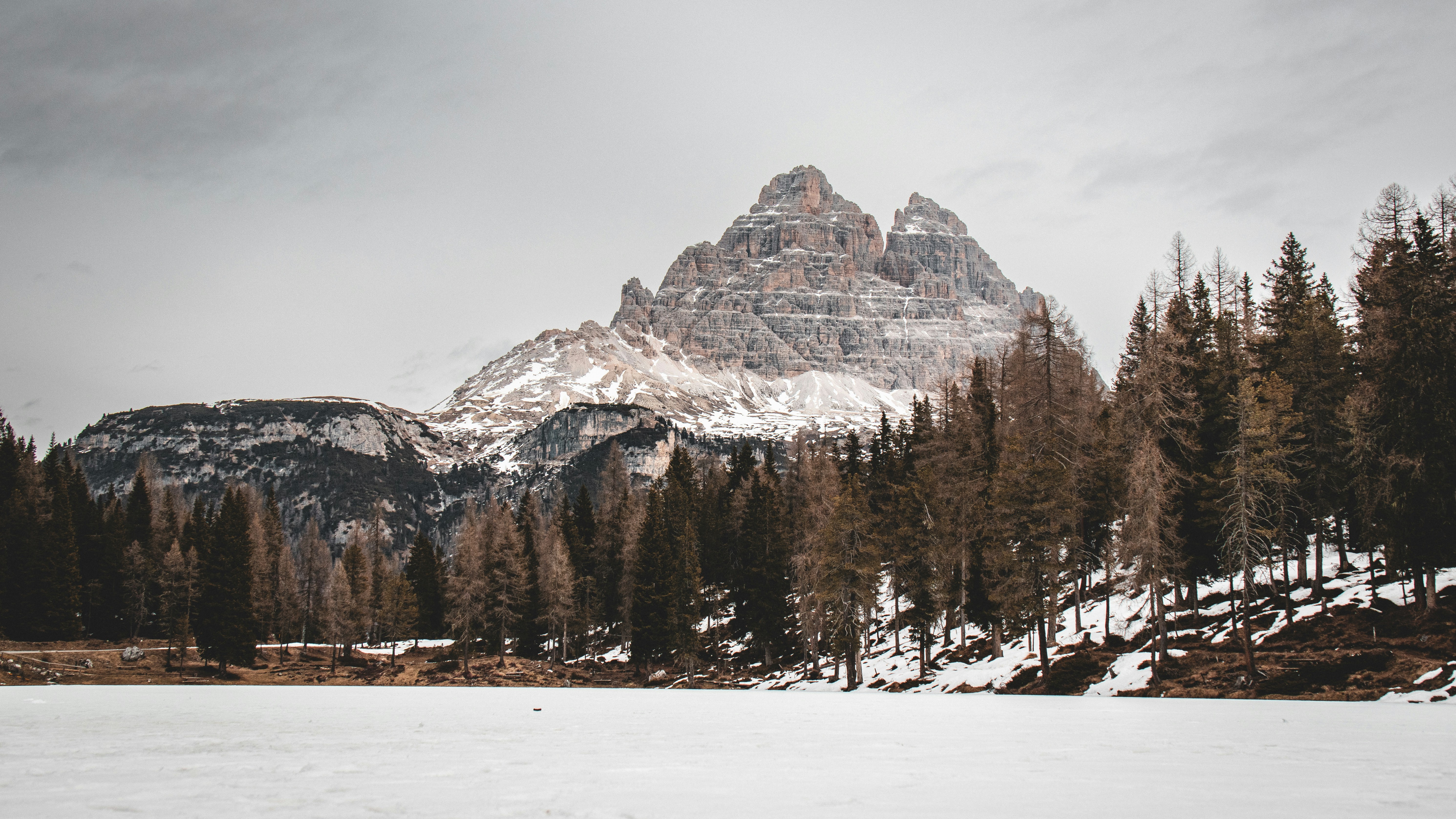a snow covered field with a mountain in the background, 